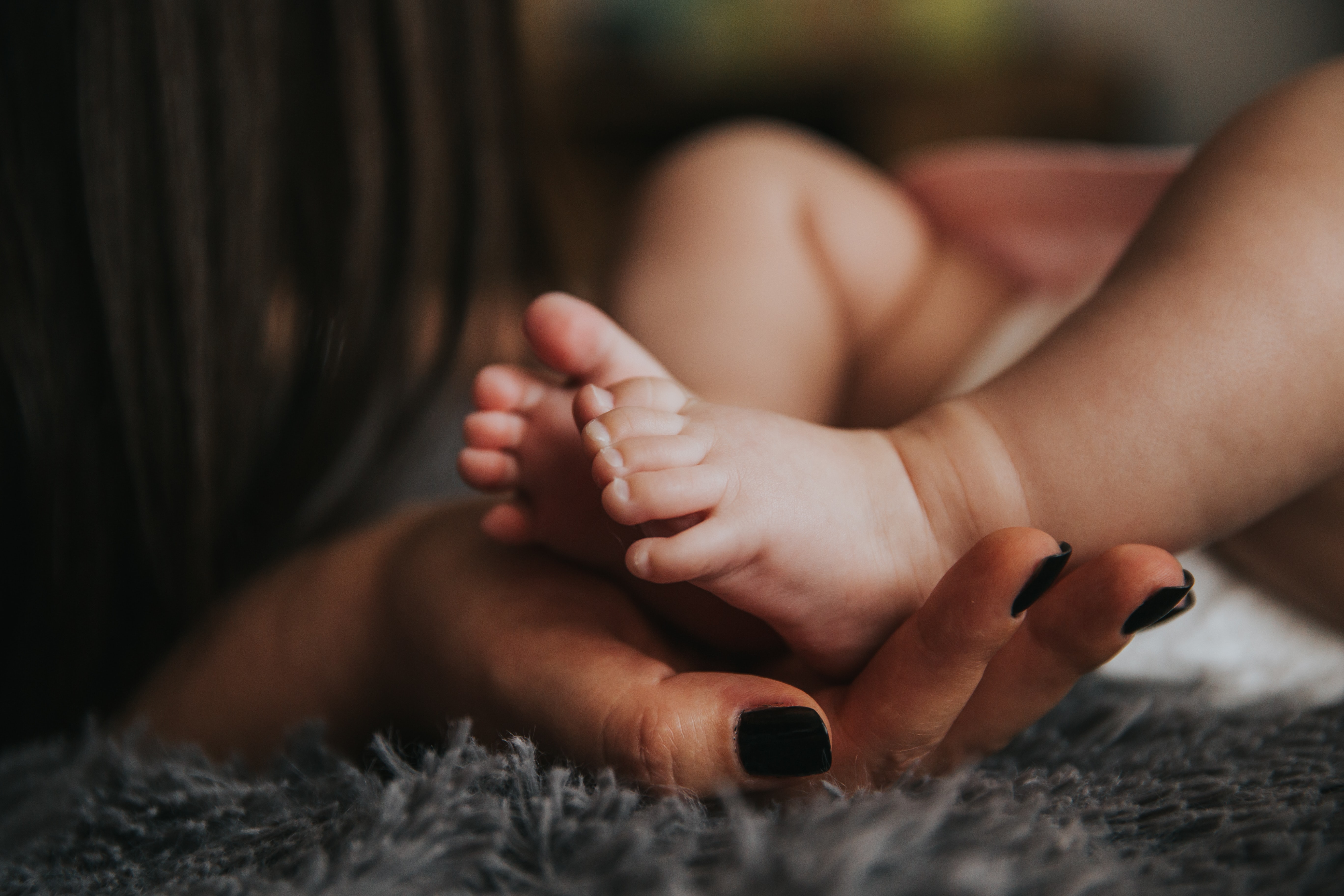 mother holding baby feet Photo by Alex Pasarelu on Unsplash