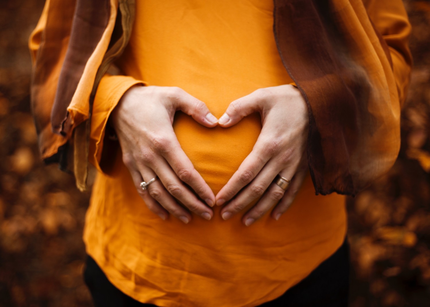 woman making heart with hands over pregnant belly Photo by Alicia Petresc on Unsplash