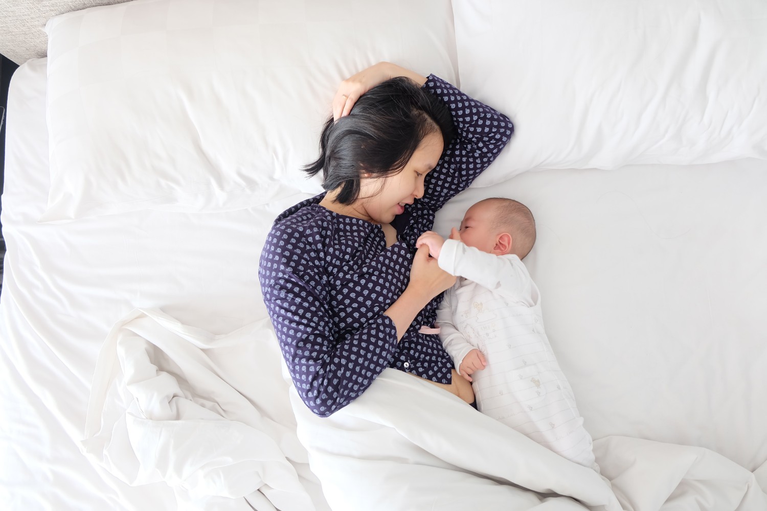 mother and baby lying in bed together Photo by kevin liang on Unsplash