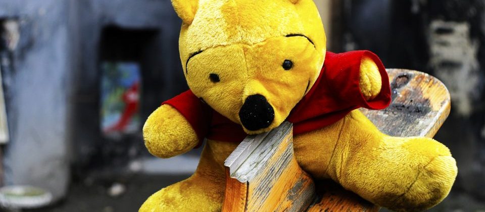 Photo of a dirty, worn stuffed animal, likely Winnie the Pooh