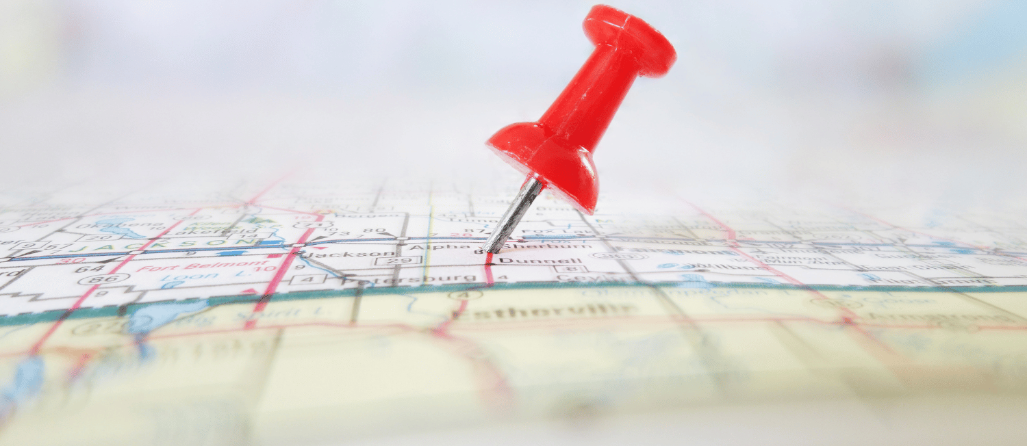 Photo of a red thumbtack stuck into a map