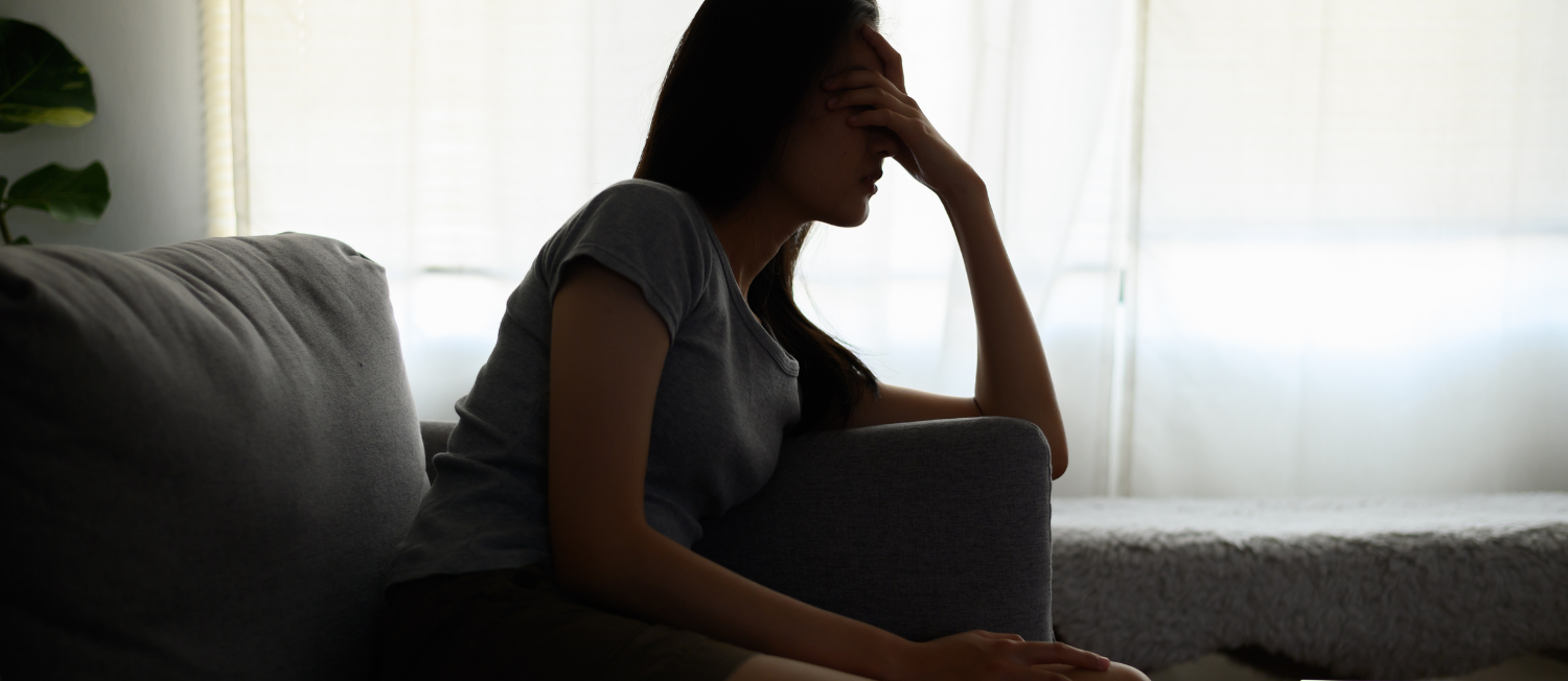 Silhouette of a person with long hair holding their head in their hands